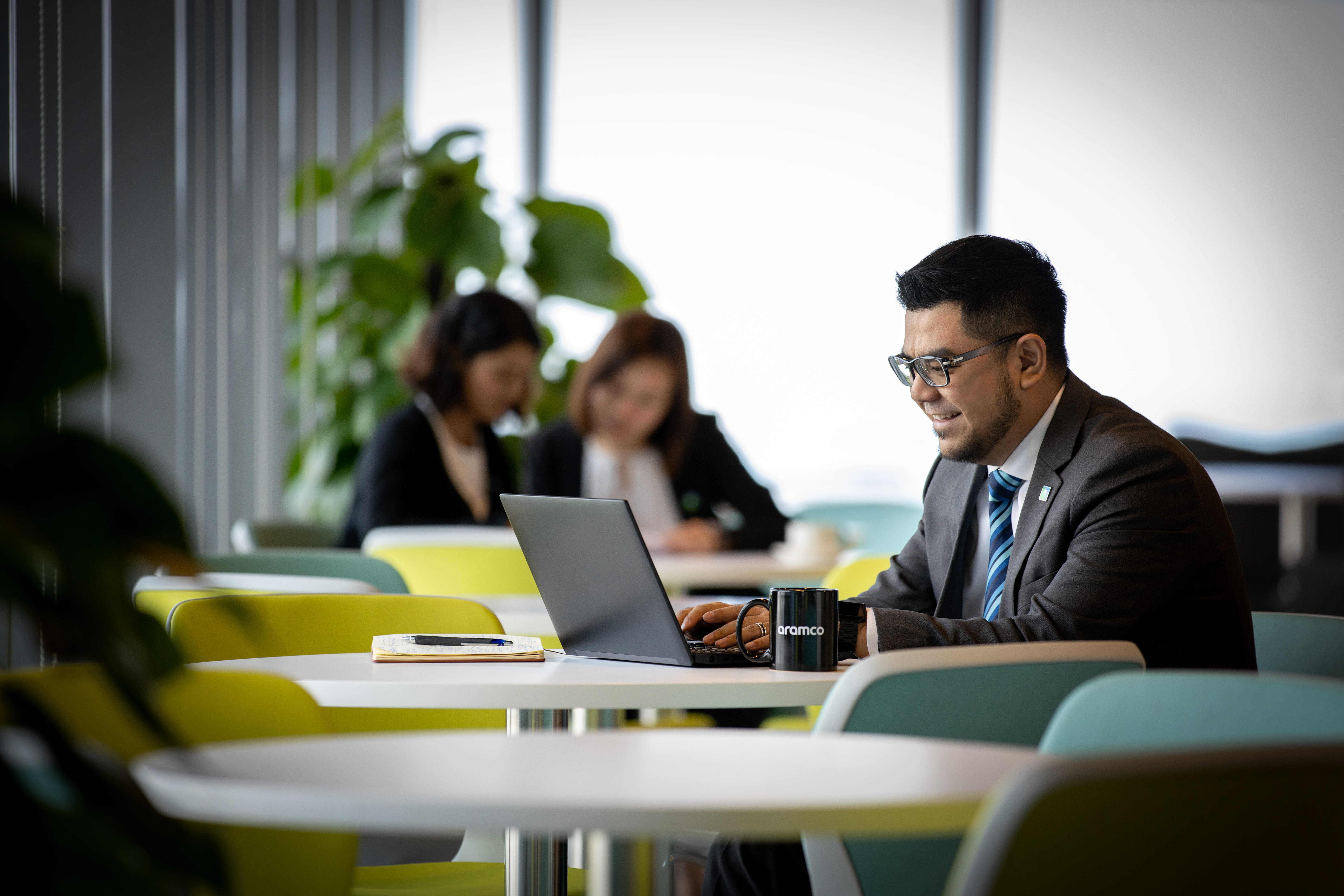 Man on laptop with two ladies in the background